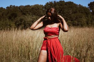 African American woman in a wheat field wearing a red outfit